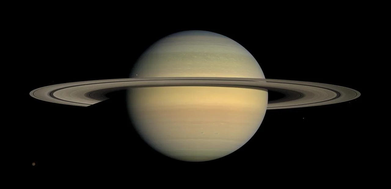 Saturn with broad rings extending far beyond the planetary globe.